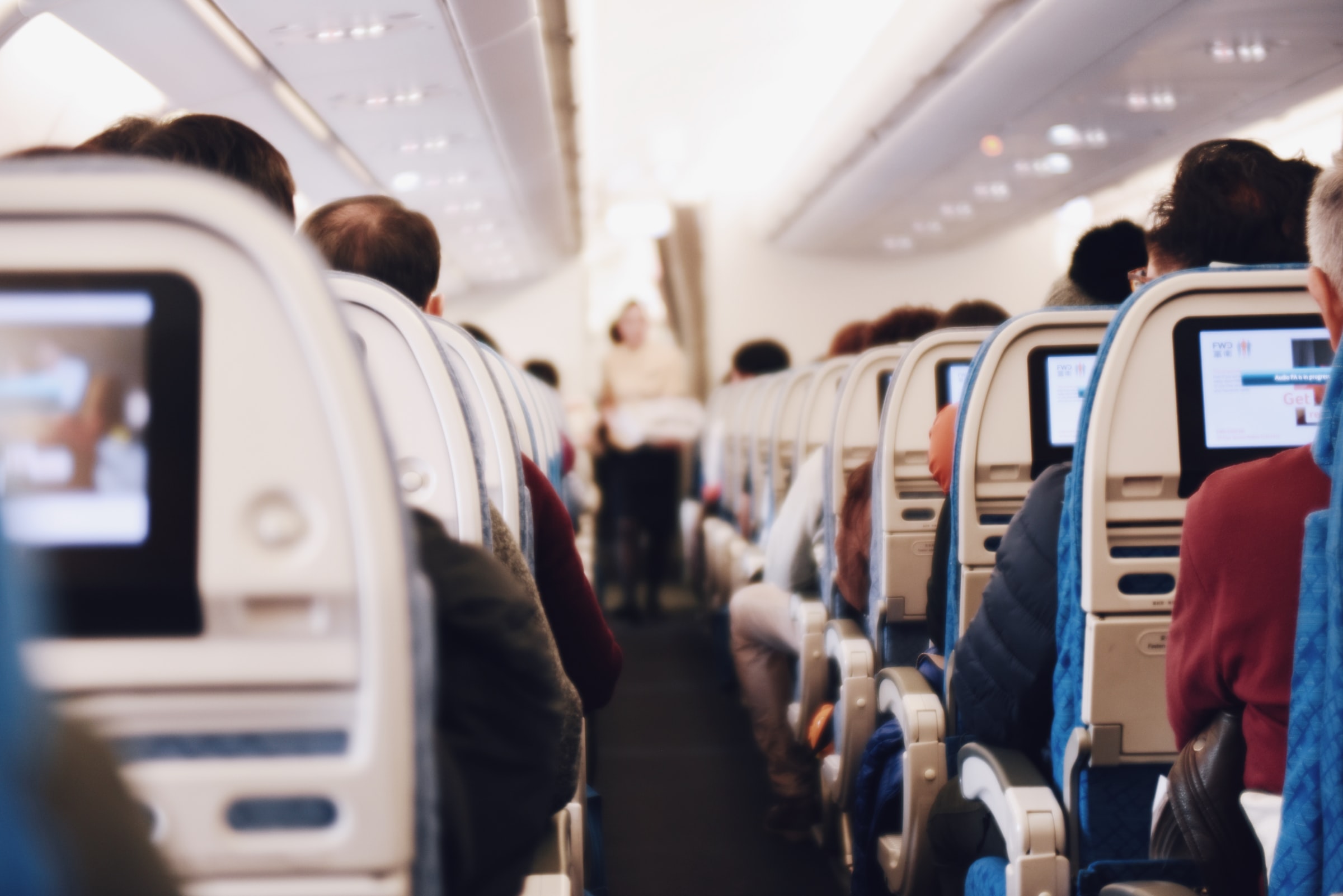 Airplane aisle during flight with inflight entertainment screens